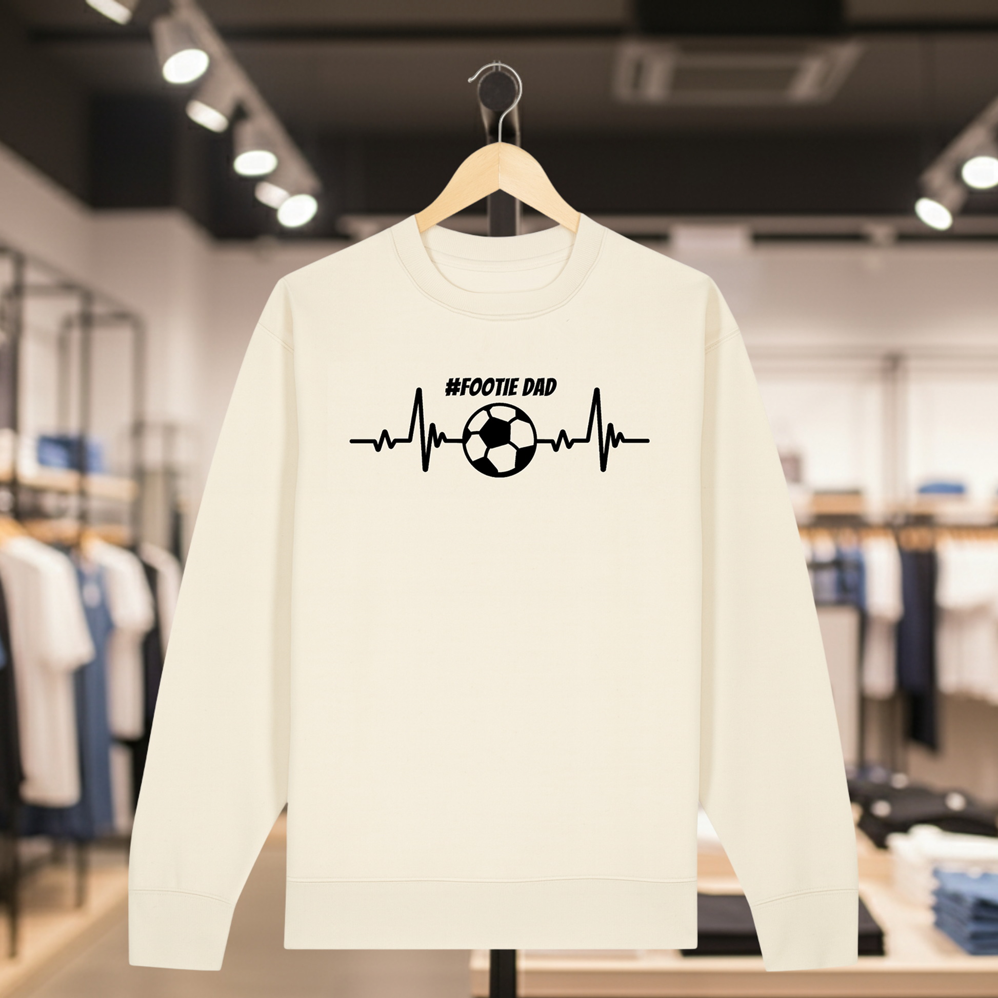 Natural sweatshirt with a white #FOOTIE DAD text on a hanger in a store setting