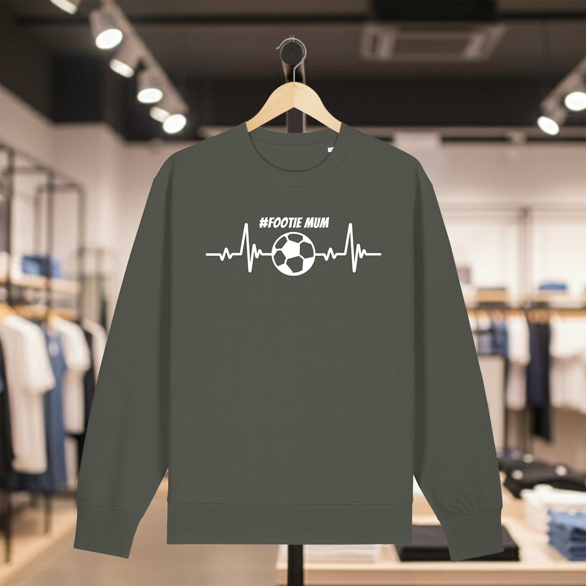 Khaki sweatshirt with a white #FOOTIE MUM text on a hanger in a store setting