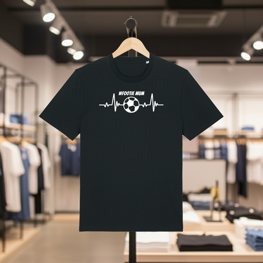 Black t-shirt with a #Footie Mum design featuring a soccer ball on a hanger in a store.