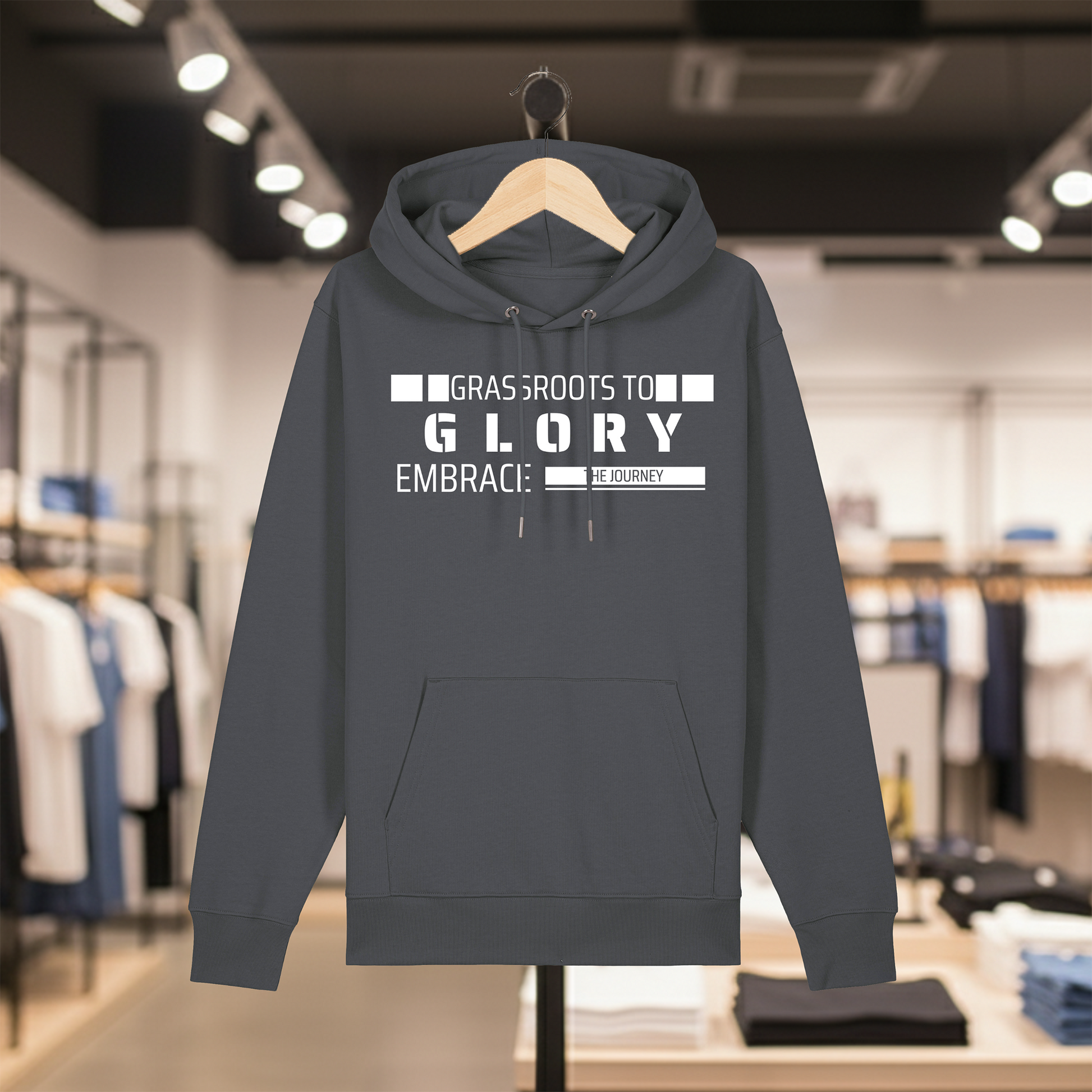 Grey hoodie with text GRASSROOTS TO GLORY on a hanger in a store setting