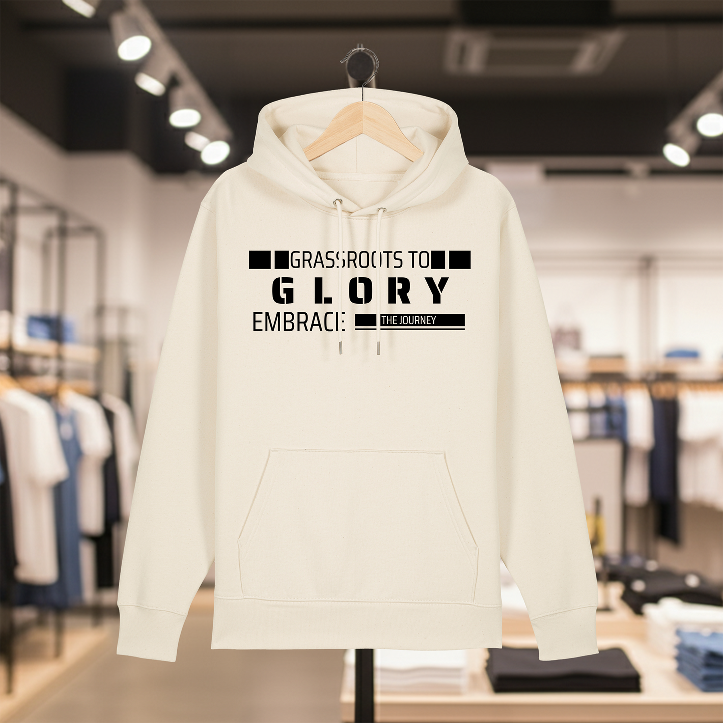 Natural hoodie with text GRASSROOTS TO GLORY on a hanger in a store setting
