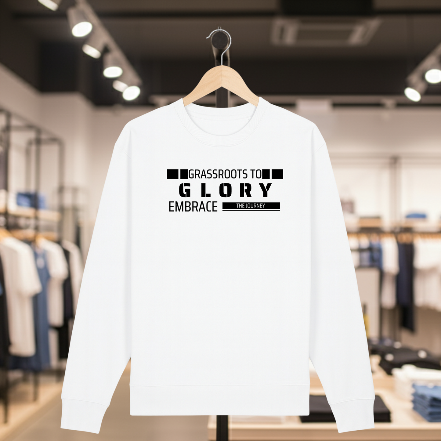White sweatshirt with text GRASSROOTS TO GLORY on a hanger in a store setting