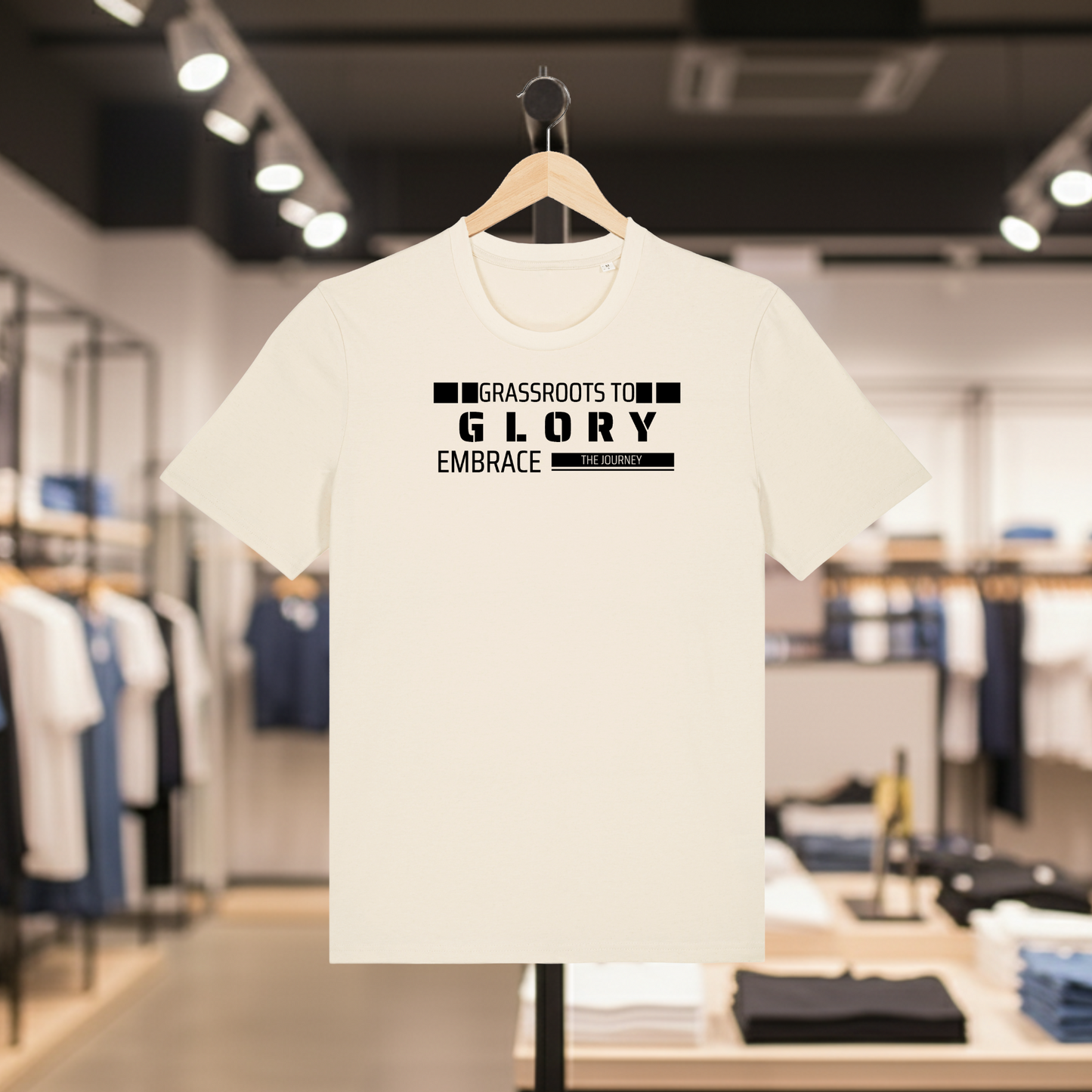 Natural t-shirt with Grassroots to Glory design on a hanger in a store setting