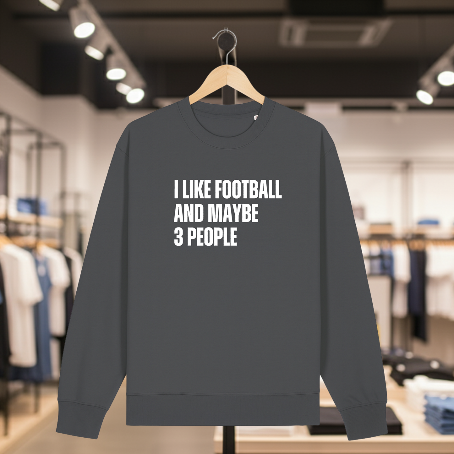 Grey sweatshirt with text I LIKE FOOTBALL AND MAYBE 3 PEOPLE on a hanger in a store.