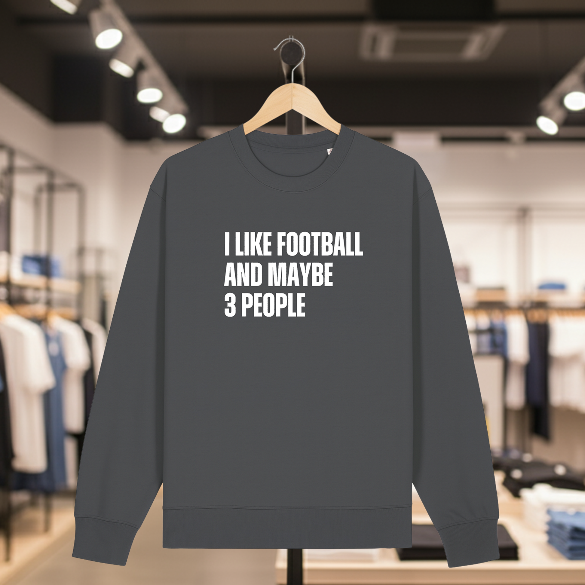 Grey sweatshirt with text I LIKE FOOTBALL AND MAYBE 3 PEOPLE on a hanger in a store.