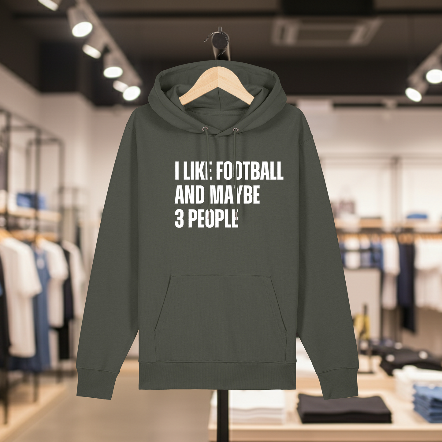 Khaki hoodie with text I LIKE FOOTBALL AND MAYBE 3 PEOPLE on a hanger in a store setting.