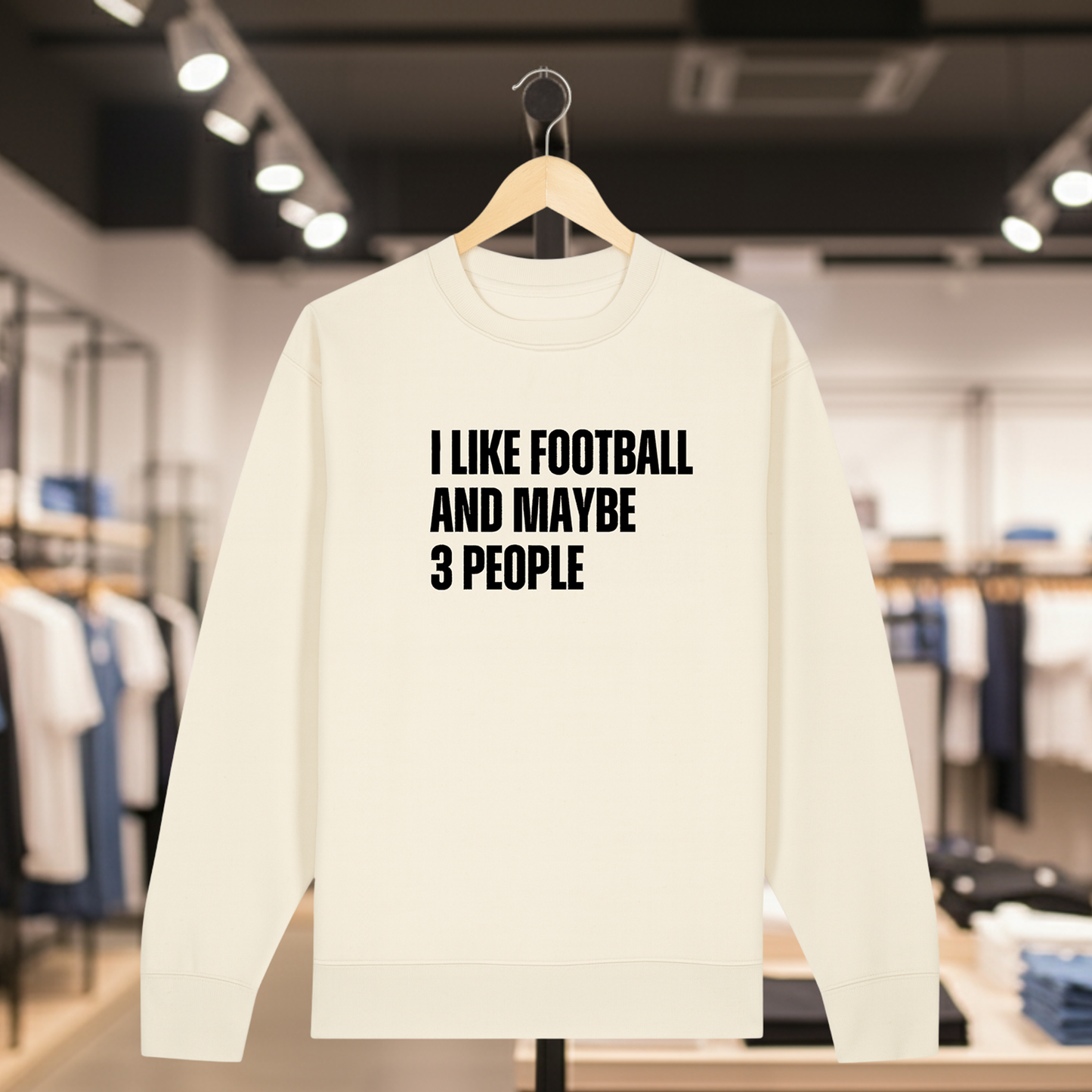Natural sweatshirt with text I LIKE FOOTBALL AND MAYBE 3 PEOPLE on a hanger in a store.