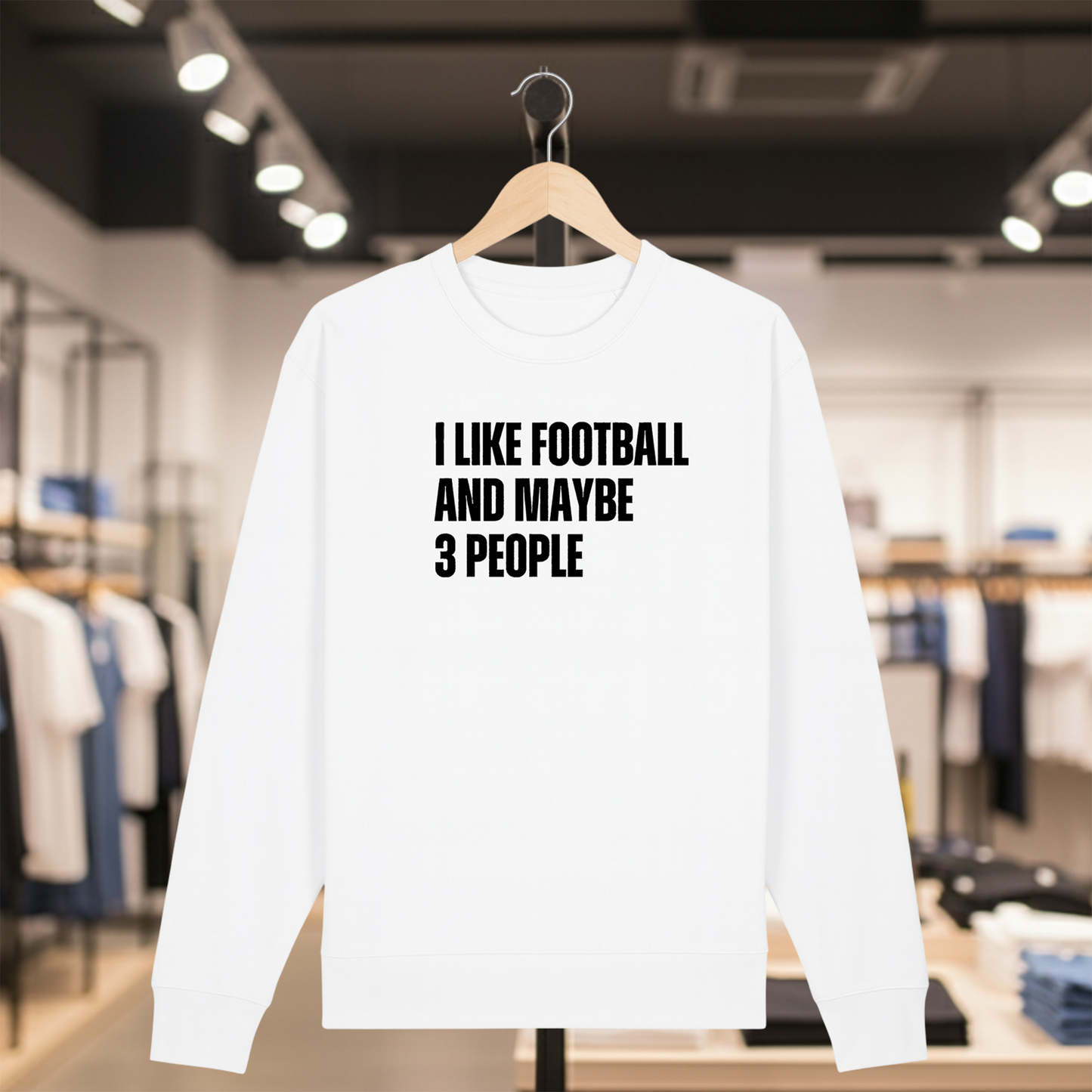 White sweatshirt with text I LIKE FOOTBALL AND MAYBE 3 PEOPLE on a hanger in a store.