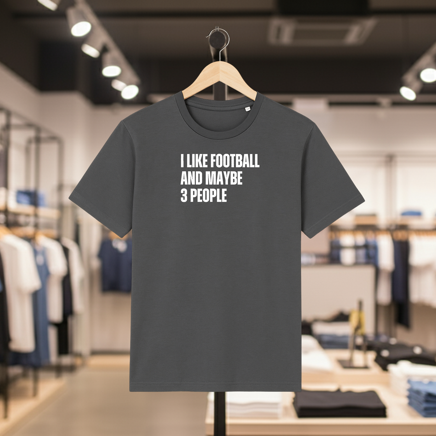 Grey t-shirt with I Like Football And Maybe 3 People text on a hanger in a store.
