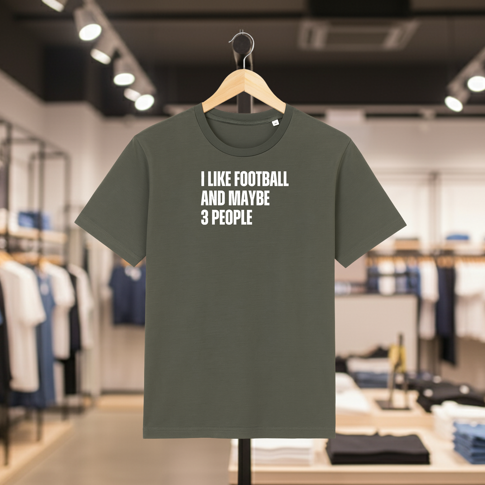 Khaki t-shirt with I Like Football And Maybe 3 People text on a hanger in a store.