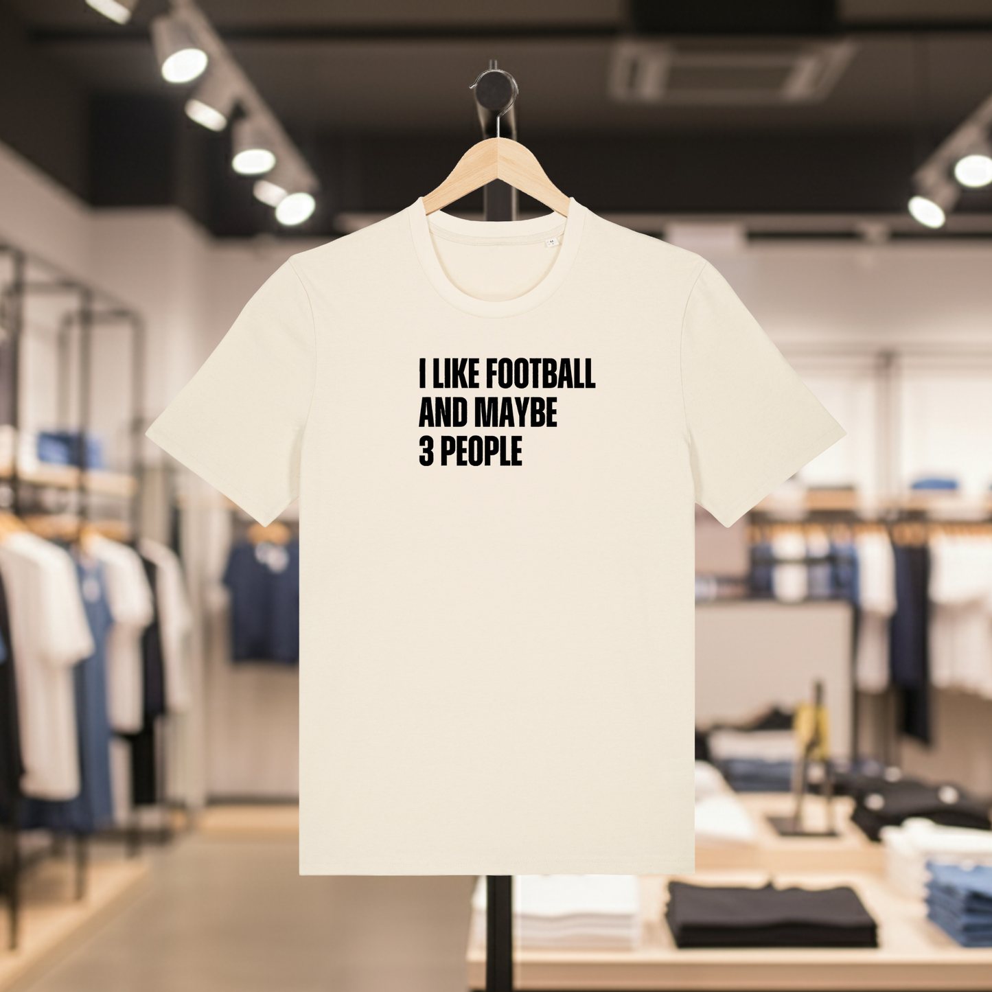Natural t-shirt with I Like Football And Maybe 3 People text on a hanger in a store.