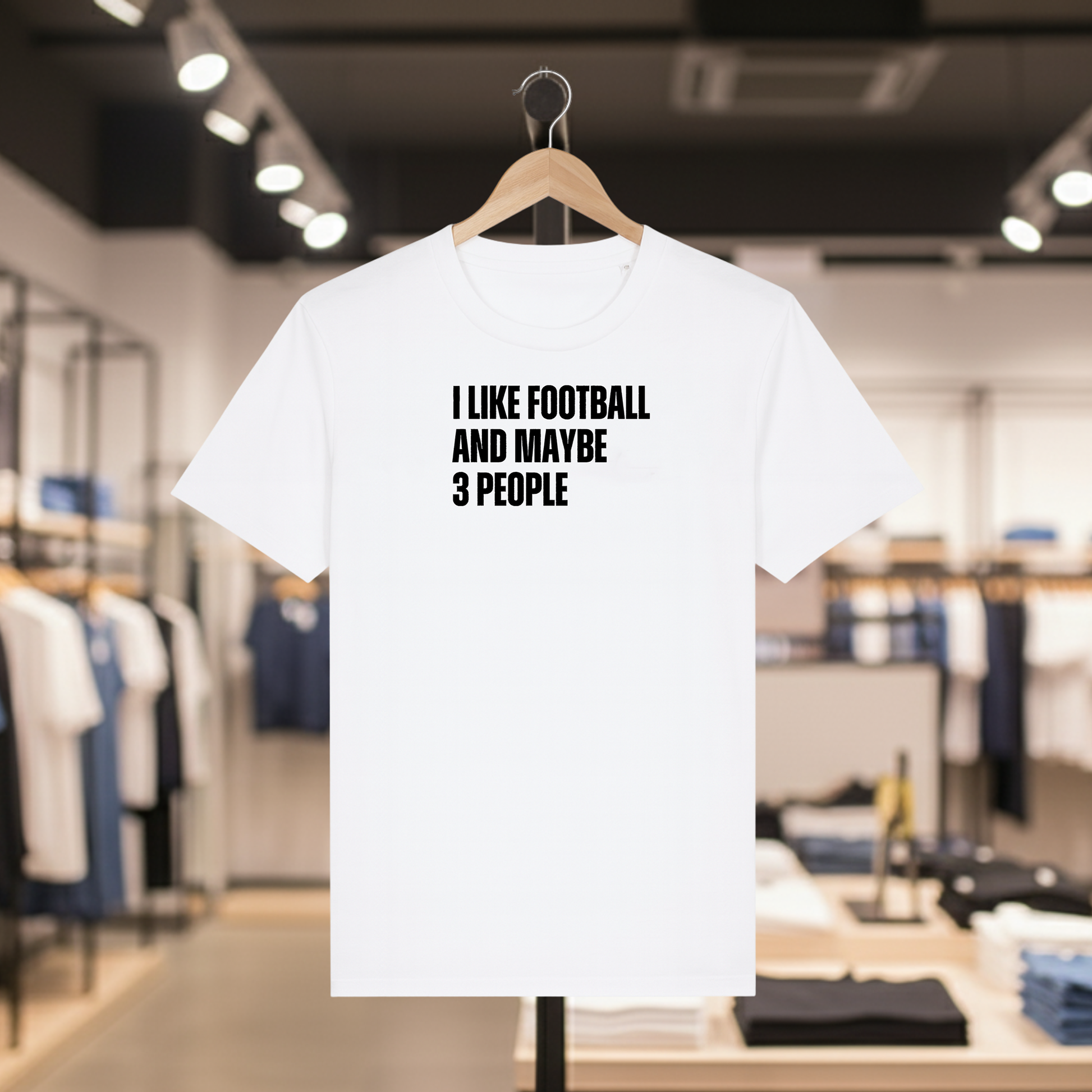 White t-shirt with I Like Football And Maybe 3 People text on a hanger in a store.