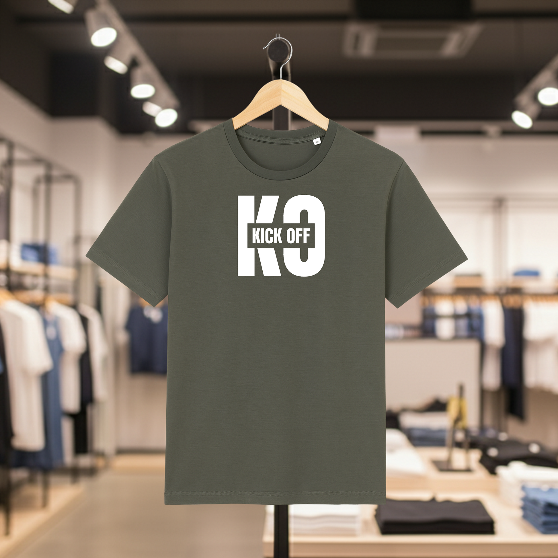 Khaki t-shirt with KICK OFF text on a hanger in a store setting