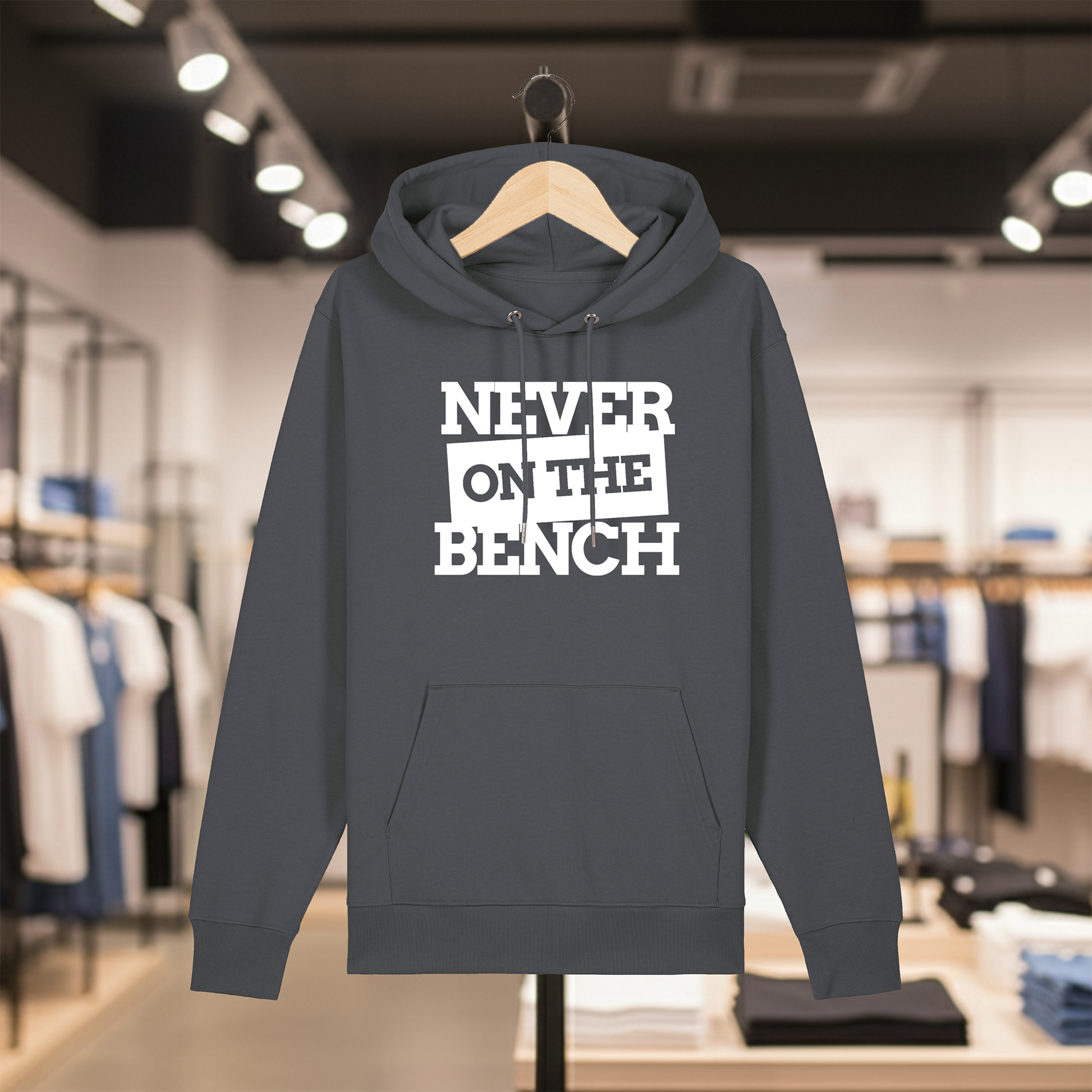 Grey hoodie with text NEVER ON THE BENCH on a hanger in a store setting
