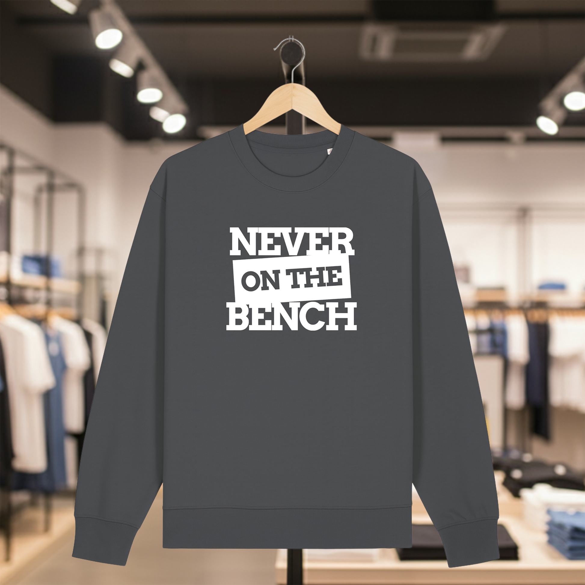 Grey sweatshirt with NEVER ON THE BENCH text on a hanger in a store setting