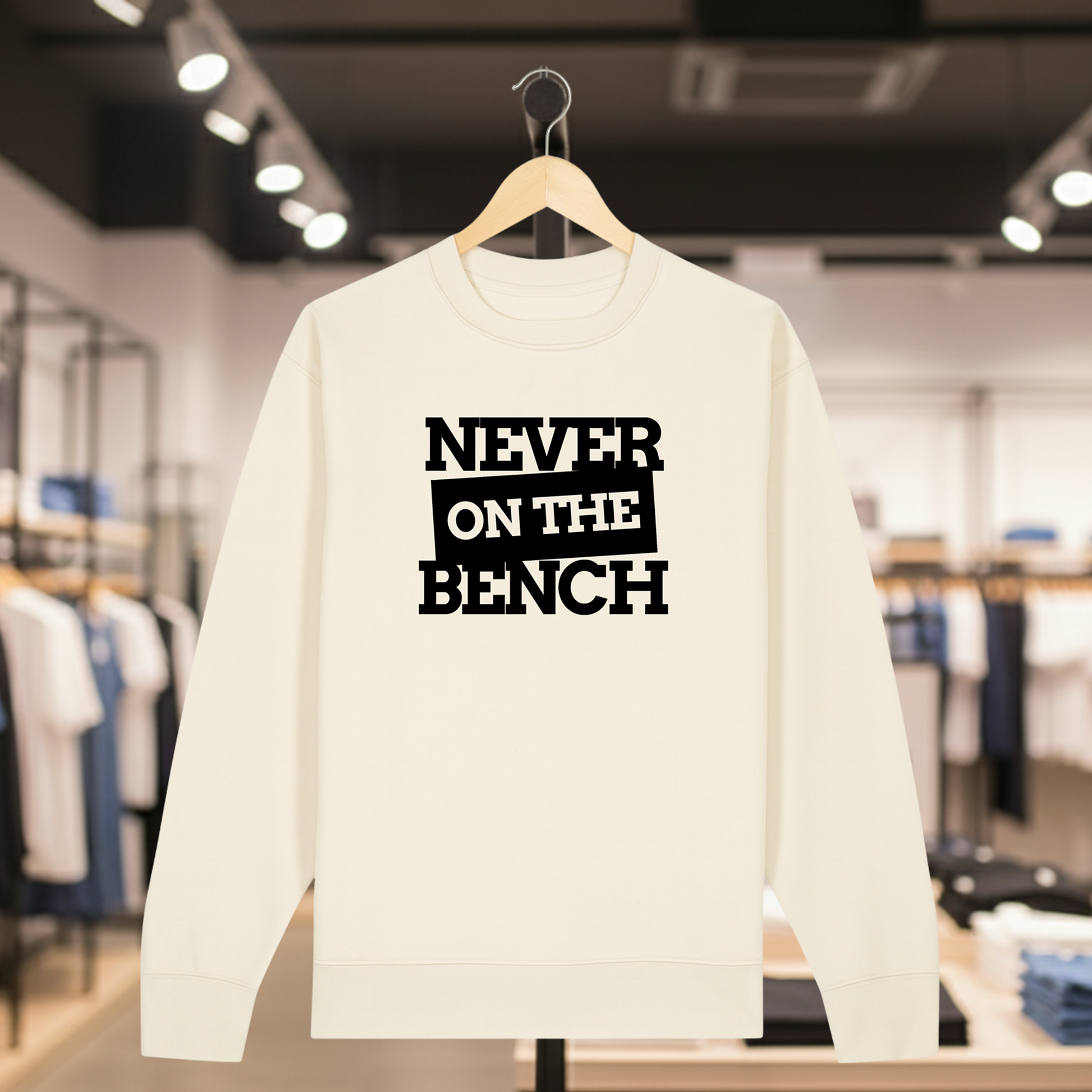 Natural sweatshirt with NEVER ON THE BENCH text on a hanger in a store setting