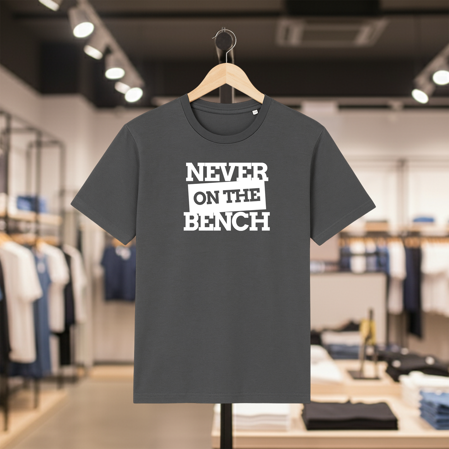 Grey t-shirt with Never on the Bench text on a hanger in a store setting