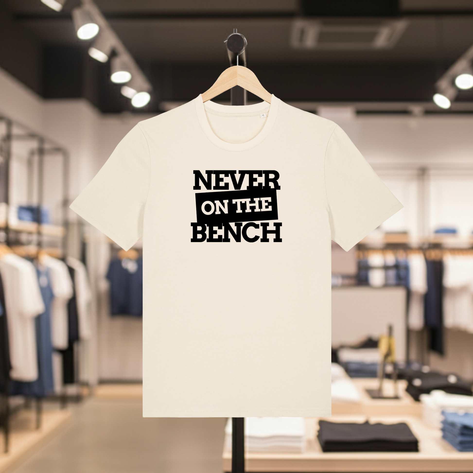 Natural t-shirt with Never on the Bench text on a hanger in a store setting