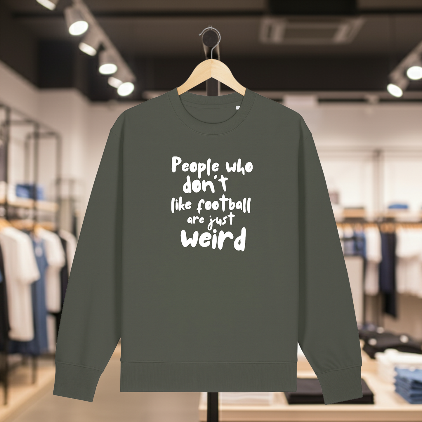 Khaki sweatshirt with white text PEOPLE WHO DON'T LIKE FOOTBALL ARE JUST WEIRD on a hanger in a store setting