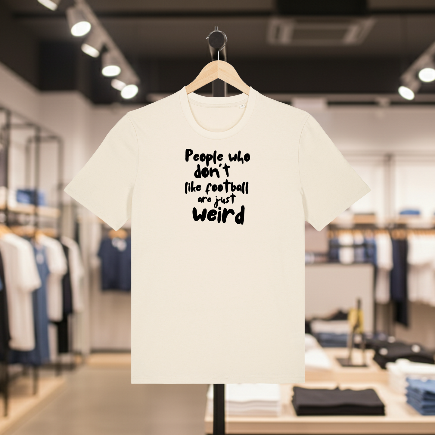 Natural t-shirt with white PEOPLE WHO DON'T LIKE FOOTBALL ARE JUST WEIRD text on a hanger in a store setting