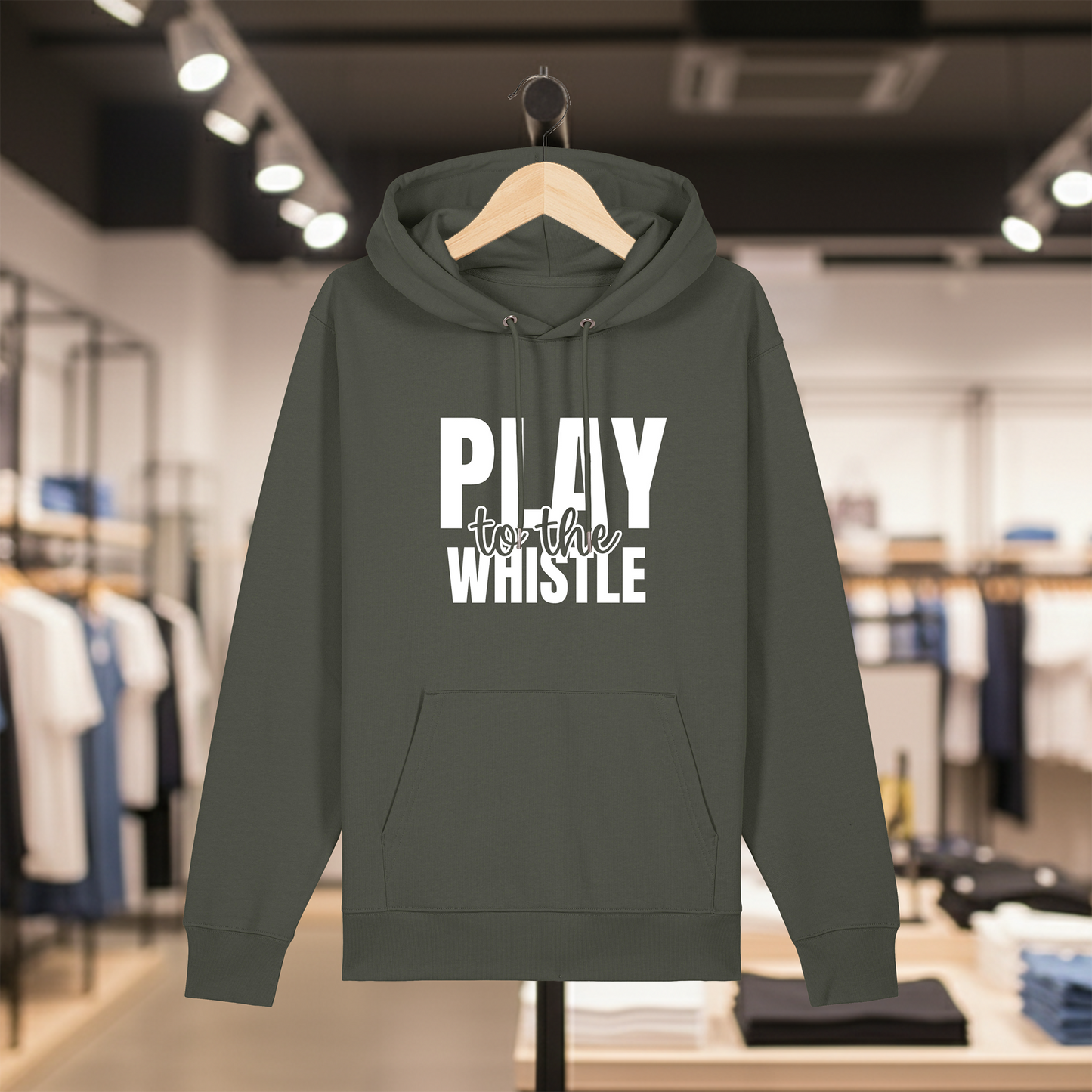 Khaki hoodie with text PLAY TO THE WHISTLE on a hanger in a store setting