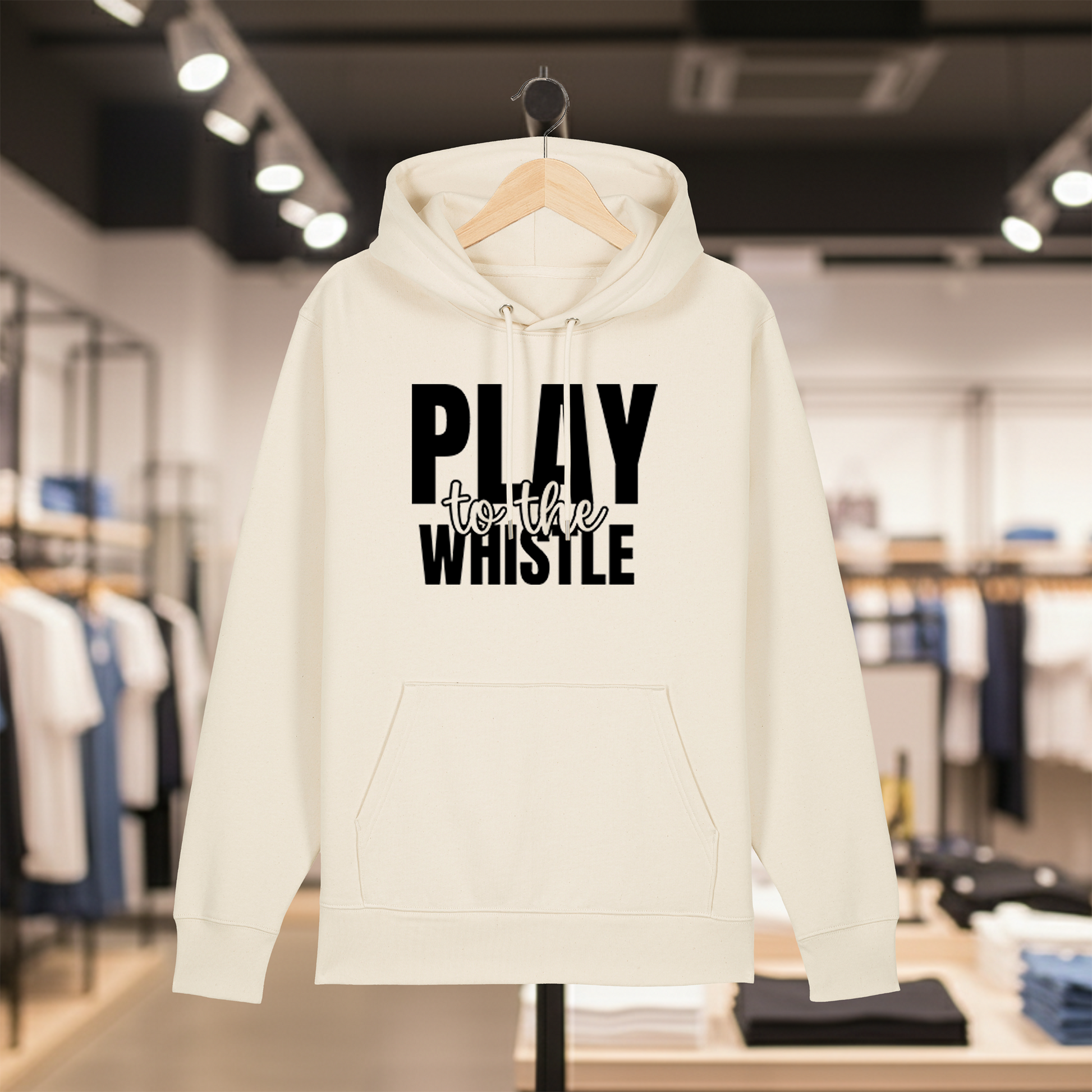 Natural hoodie with text PLAY TO THE WHISTLE on a hanger in a store setting