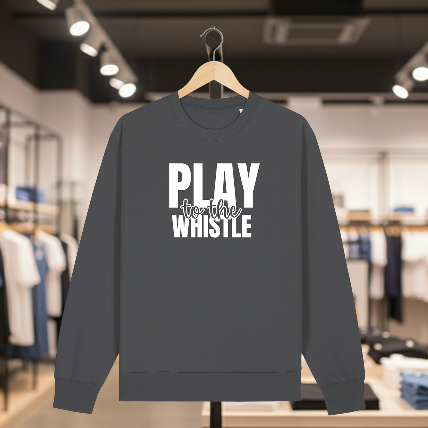 Grey sweatshirt with PLAY TO THE WHISTLE text on a hanger in a store setting