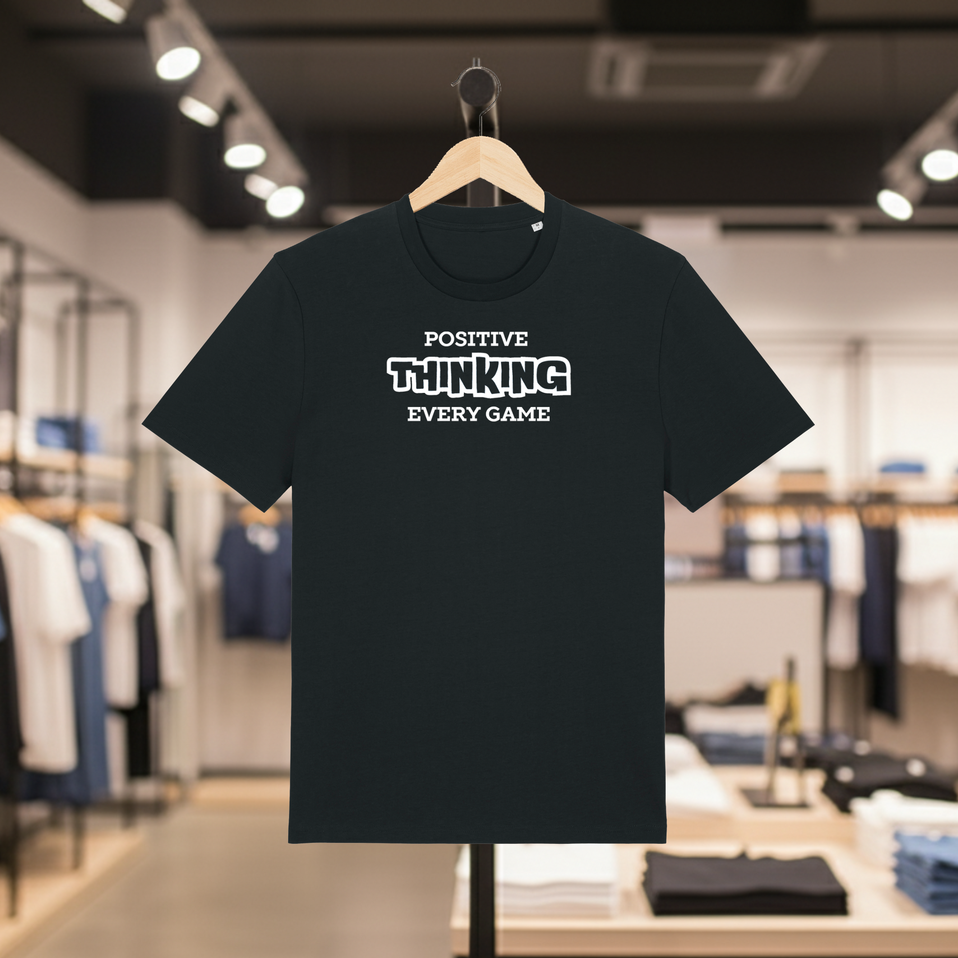 Black t-shirt with POSITIVE THINKING EVERY GAME text on a hanger in a store setting.