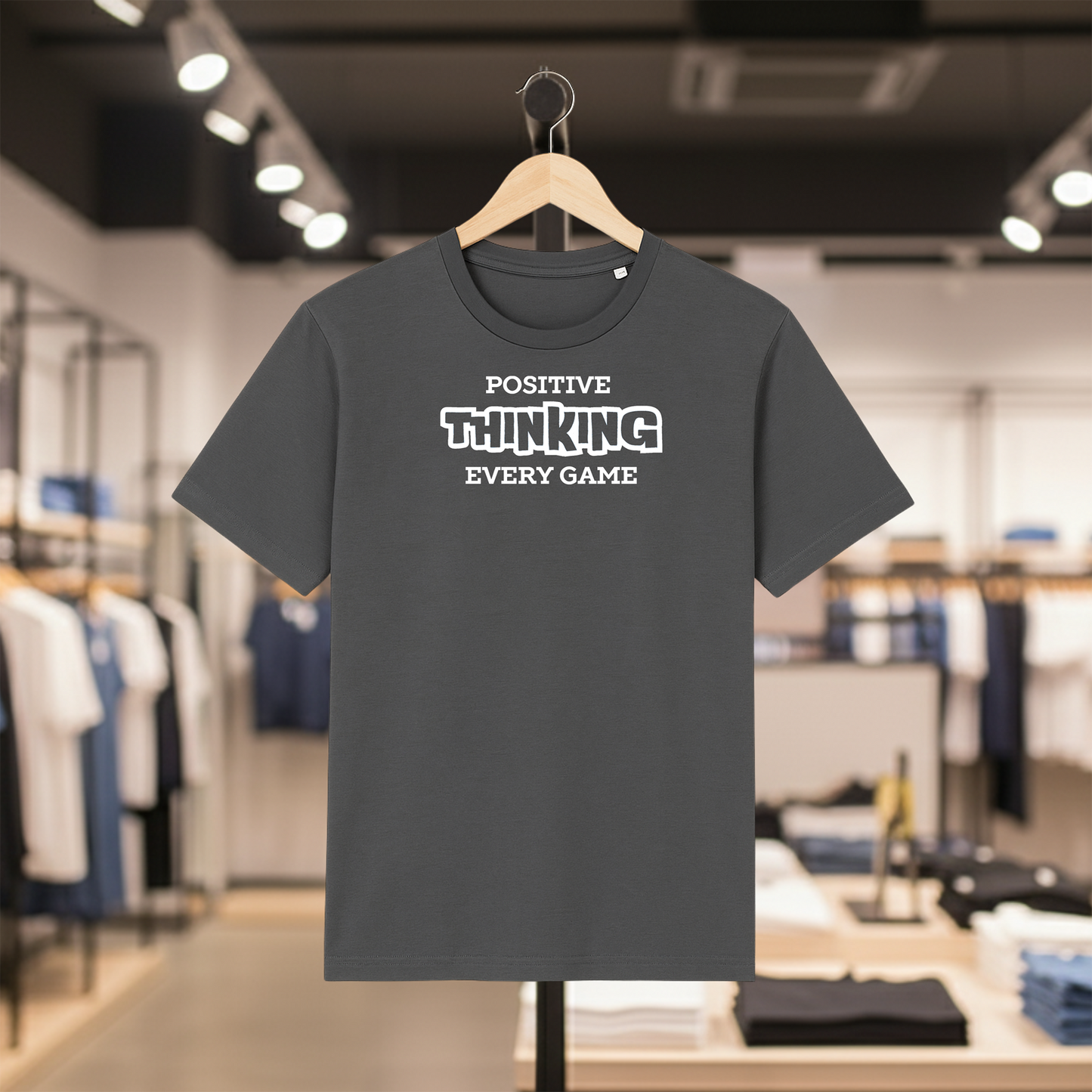 Grey t-shirt with POSITIVE THINKING EVERY GAME text on a hanger in a store setting.