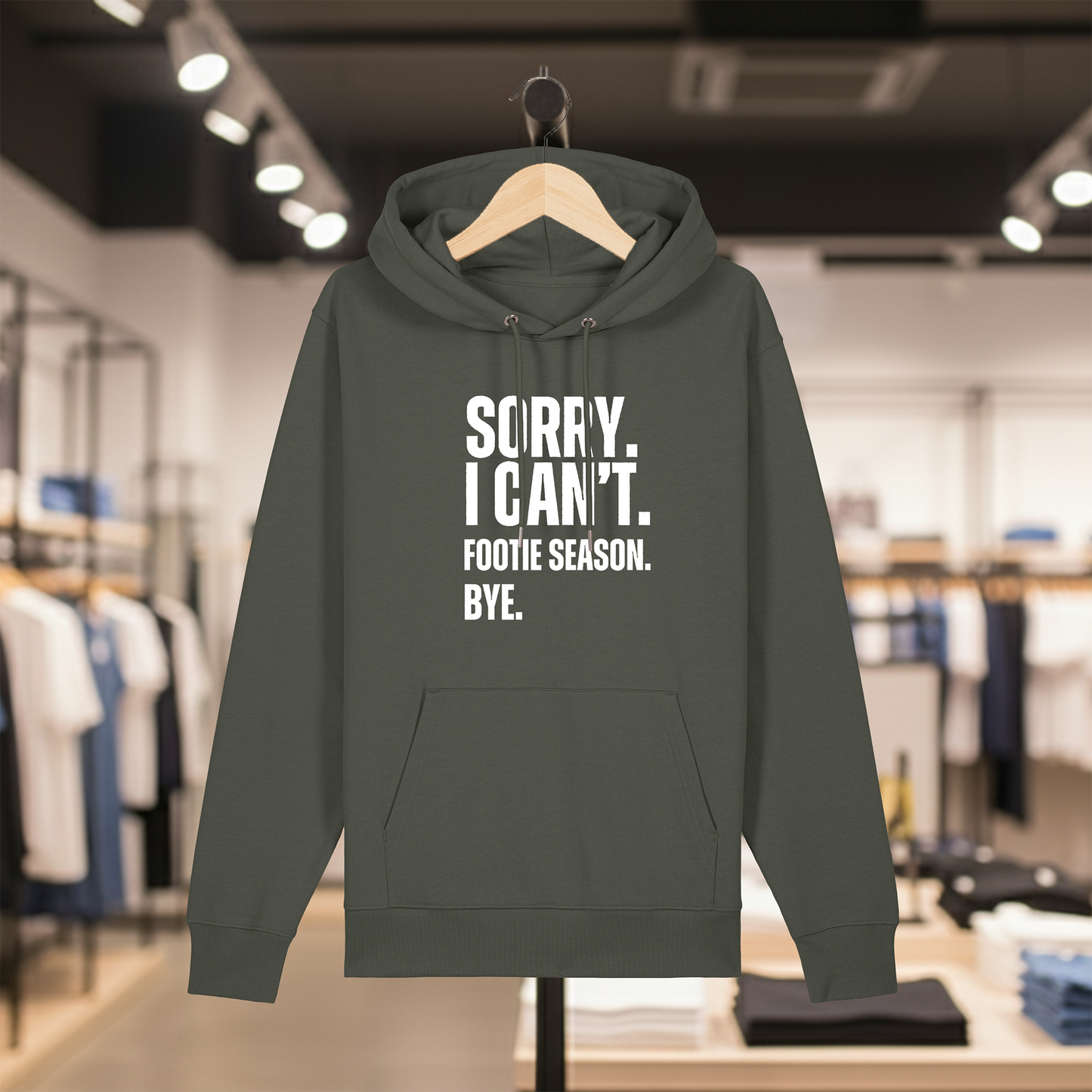 Khaki hoodie with text SORRY. I CAN'T. FOOTIE SEASON. BYE. on a hanger in a store setting