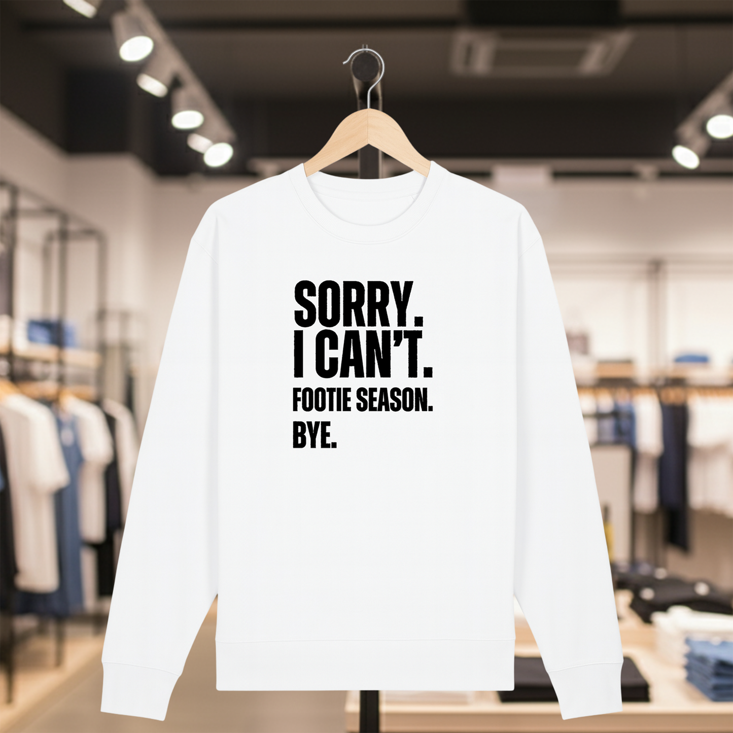 White sweatshirt with white text SORRY. I CAN'T. FOOTIE SEASON. BYE. on a hanger in a store setting