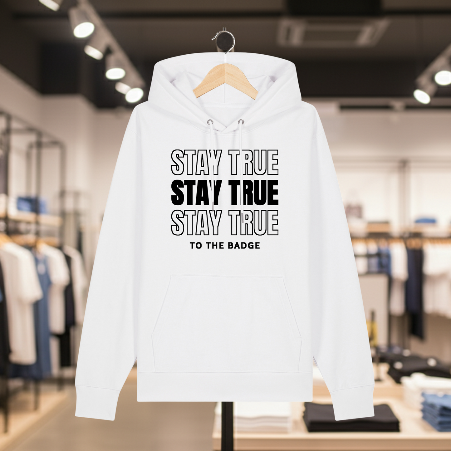 White hoodie with text STAY TRUE TO THE BADGE on a hanger in a store setting