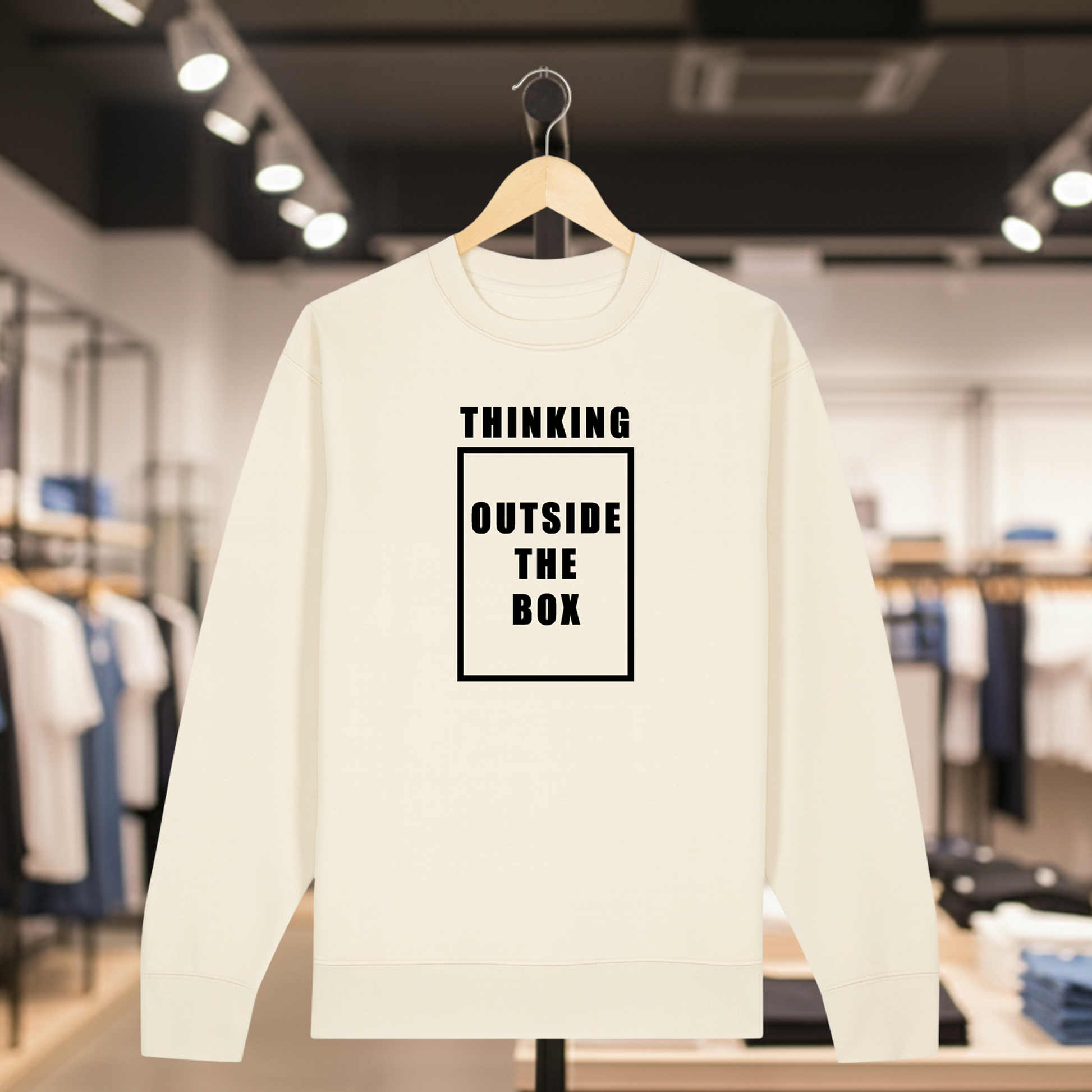 Natural sweatshirt with white text THINKING OUTSIDE THE BOX on a hanger in a store setting