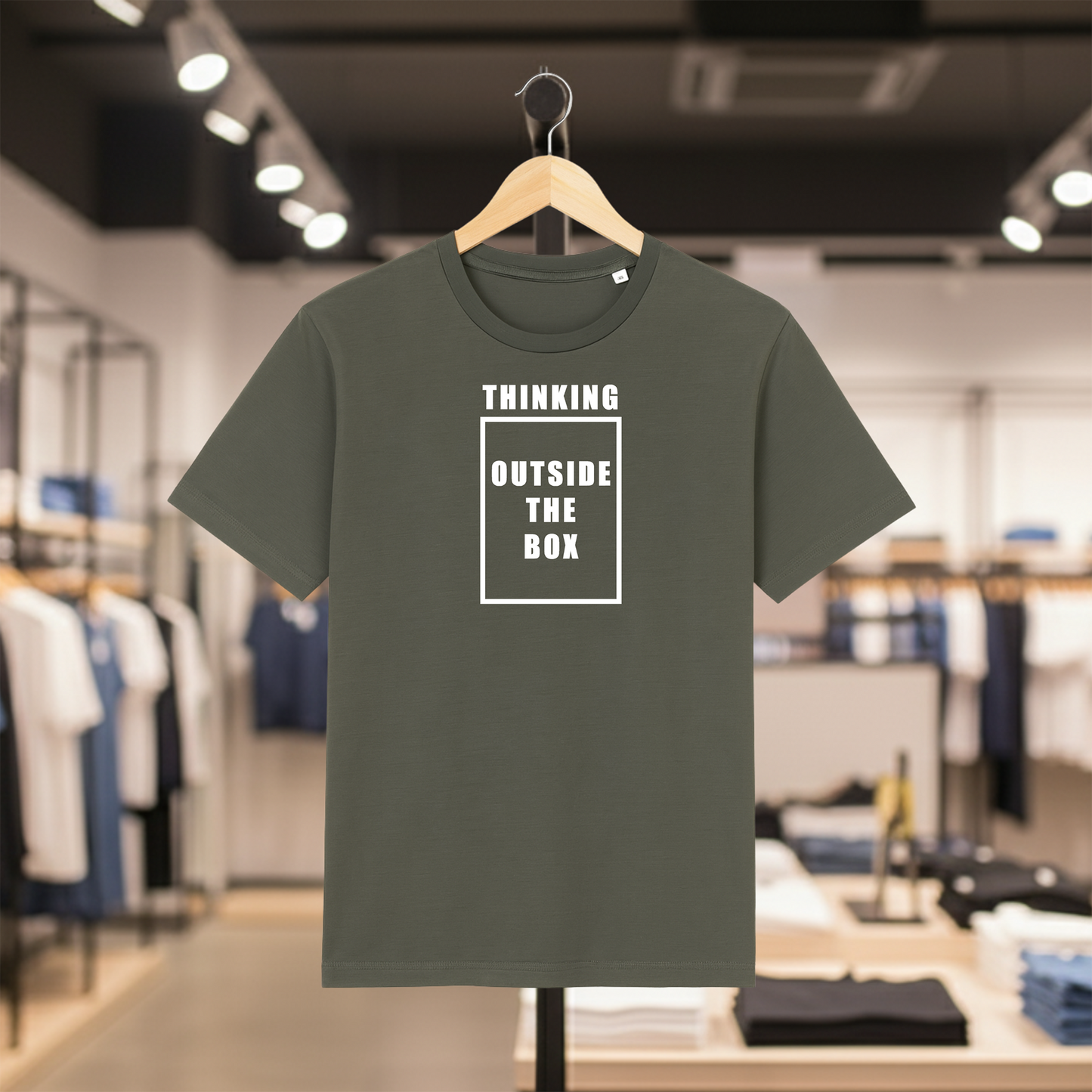 Khaki t-shirt with THINKING OUTSIDE THE BOX text on a hanger in a store setting