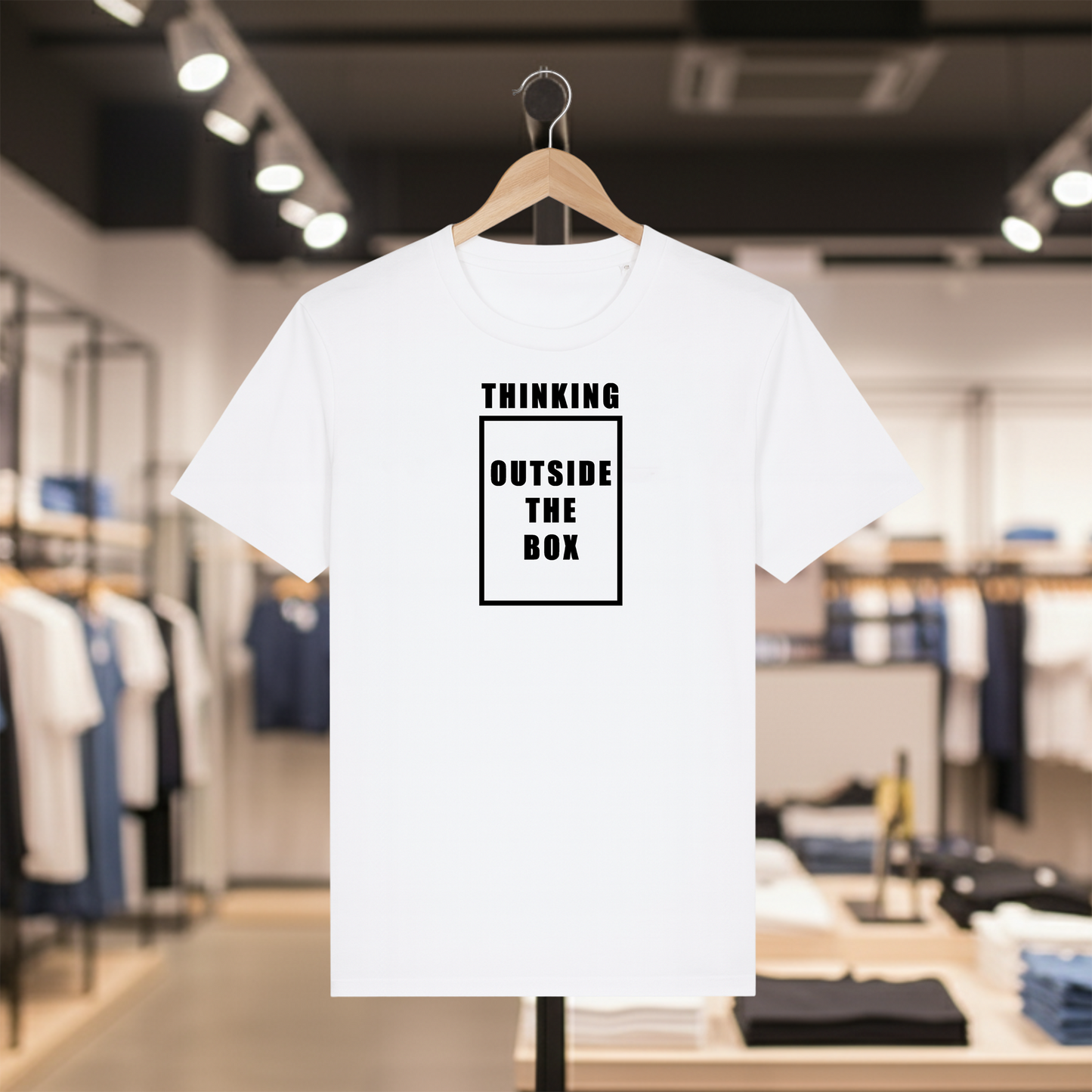 White t-shirt with THINKING OUTSIDE THE BOX text on a hanger in a store setting
