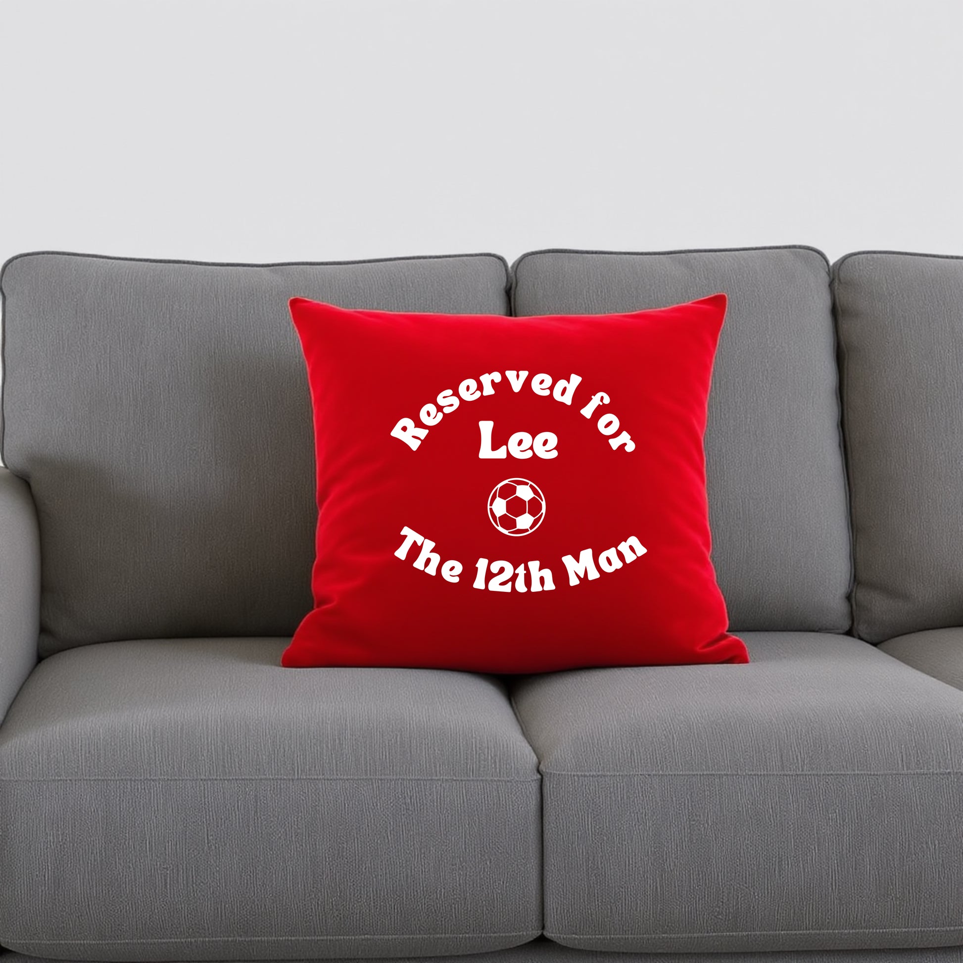 Red cushion with personalisation and a football graphic on a grey sofa